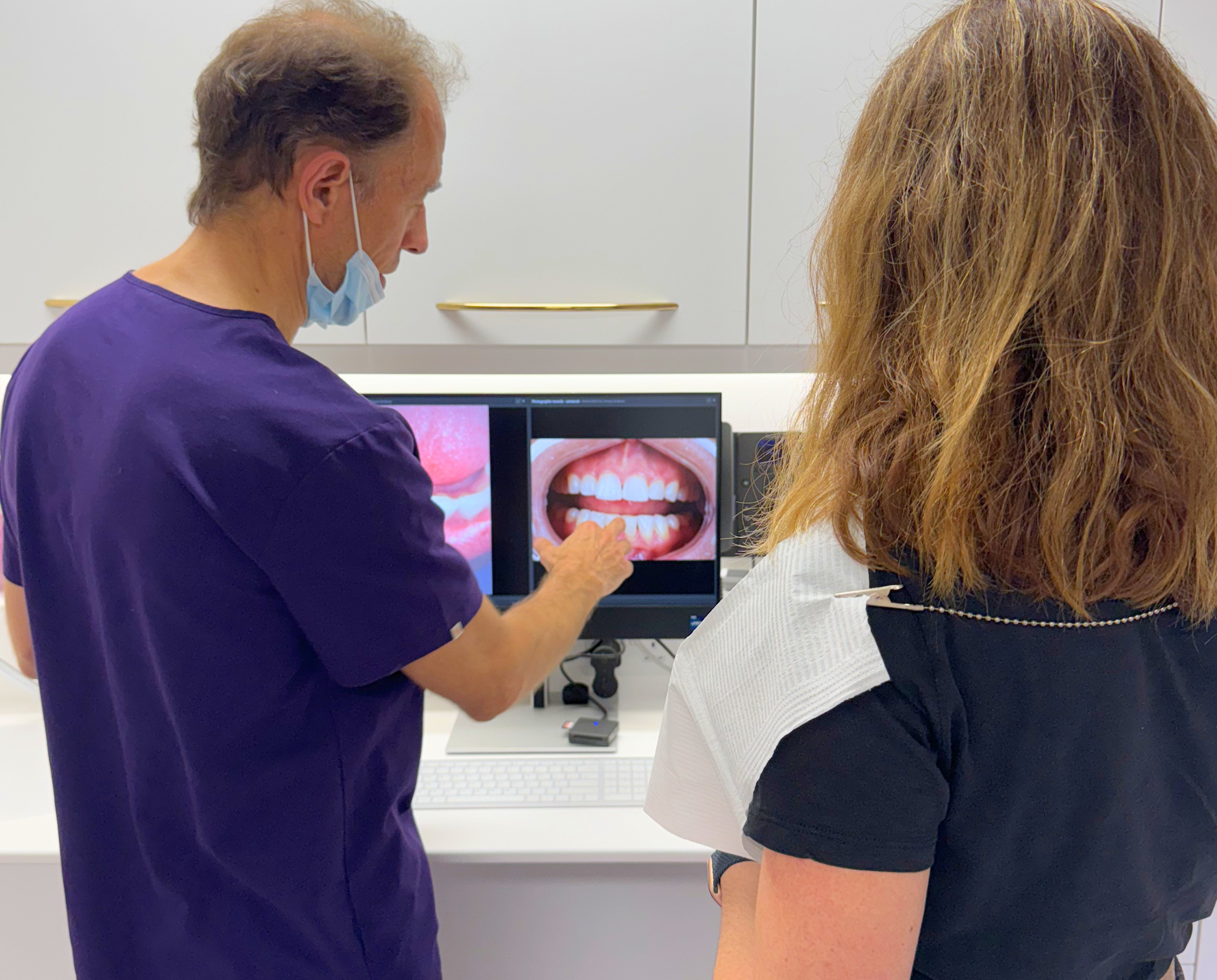 an image of dr james goolnik showing a patient a photos of their teeth in a clinical dentall setting london