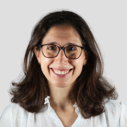 an image of alison goolnik on a grey background wearing a white blouse