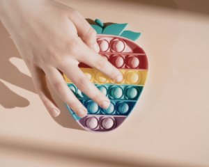 a close up photo of a figet toy to promote autism awareness being held by a childs hand