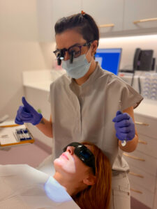 a photo of root canal therapist anna galanoudi working with a patient wearing dental glasses for protection