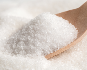 a stock image of a close up image of sugar granules on a wooden spoon