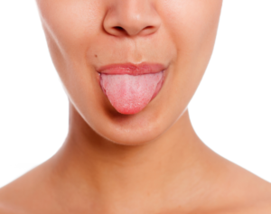 benefits of tongue scraping an image of a womans mouth up close sticking her tongue out playfully with a plain white background behind