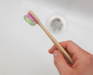 a stock image of a bamboo toothbrush being held over the sink