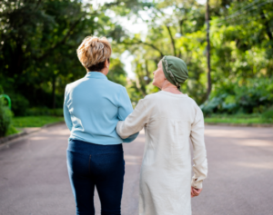 image of a cancer patient walking along the forest with her friend or family member